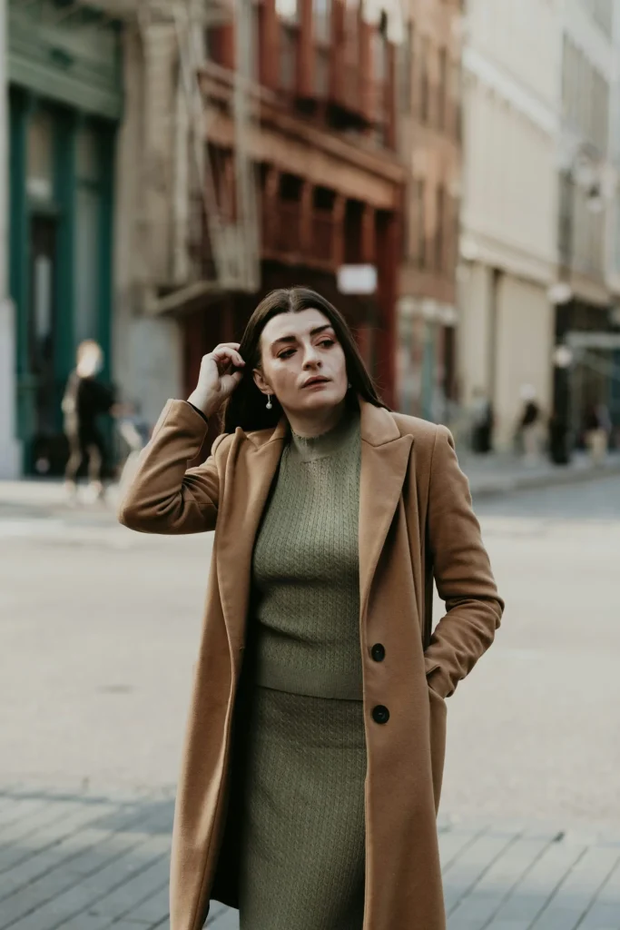 woman-in-brown-coat-standing-on-sidewalk-during-daytime-scaled