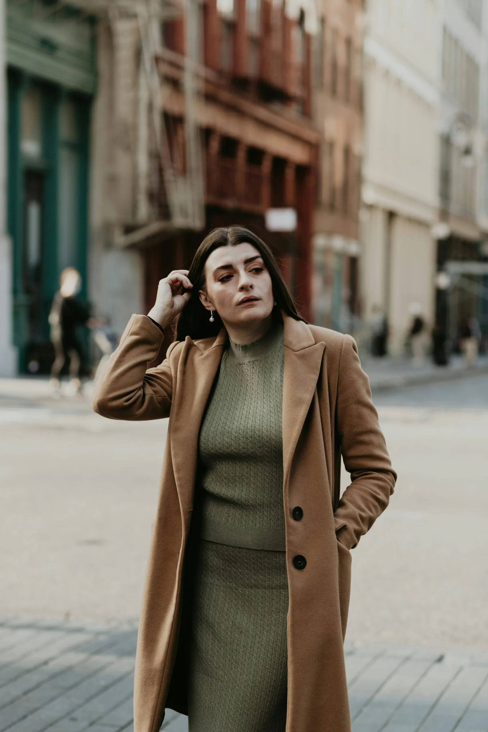 woman-in-brown-coat-standing-on-sidewalk-during-daytime-scaled