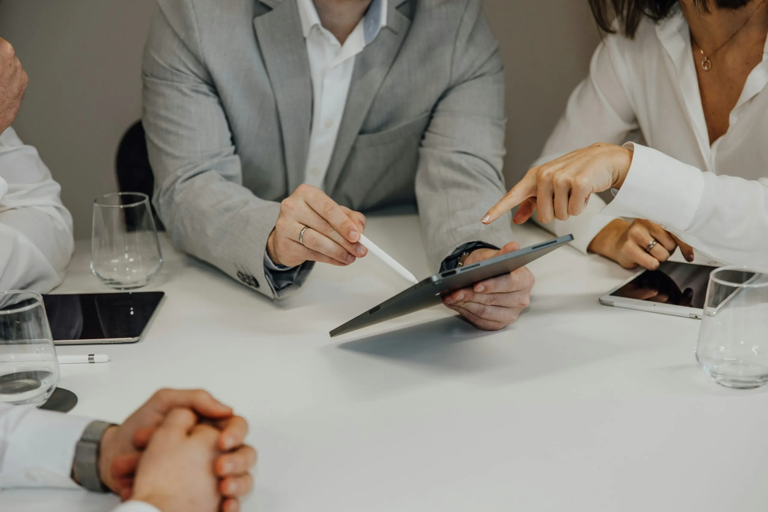 a-group-of-people-sitting-around-a-table-with-a-pair-of-scissors-scaled