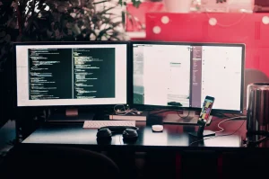 two-black-computer-monitors-on-black-table-scaled